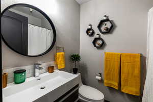 Bathroom featuring vanity, toilet, and tasteful backsplash