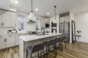 Kitchen with white cabinetry, a center island with sink, appliances with stainless steel finishes, and sink