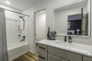 Full bathroom with hardwood / wood-style floors, toilet, vanity, and shower / tub combo