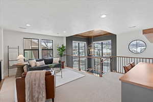 Living room with carpet floors, a textured ceiling, and plenty of natural light