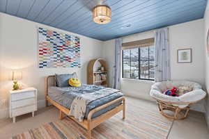 Bedroom with wooden ceiling and light colored carpet