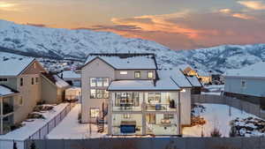 Snow covered property featuring a mountain view, a balcony, and a jacuzzi