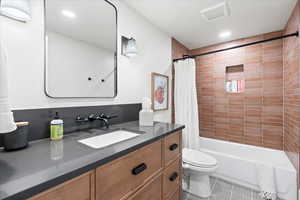 Full bathroom with vanity, shower / tub combo, tile patterned flooring, and toilet