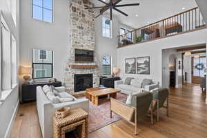 Living room with ceiling fan, hardwood / wood-style flooring, and a stone fireplace