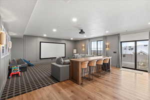 Cinema with light hardwood / wood-style flooring and a textured ceiling