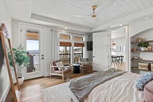 Primary Bedroom featuring access to exterior, wooden ceiling, light hardwood / wood-style floors, and a raised ceiling