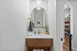 Bathroom with hardwood / wood-style flooring, decorative backsplash, and vanity