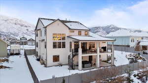 Snow covered property with a mountain view and a balcony