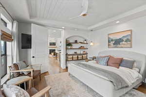 Primary Bedroom with a tray ceiling, ceiling fan, light hardwood / wood-style floors, and wood ceiling