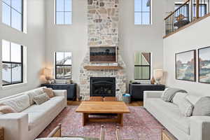 Living room with a stone fireplace, a towering ceiling, and hardwood / wood-style floors