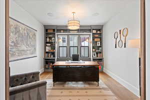 Home office with light hardwood / wood-style flooring and a textured ceiling