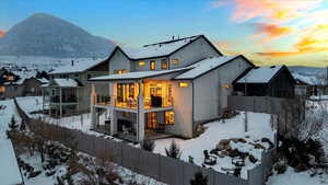 Snow covered property with a mountain view and a balcony