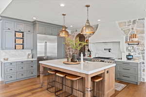 Kitchen with stainless steel built in fridge, premium range hood, a breakfast bar, sink, and a kitchen island with sink