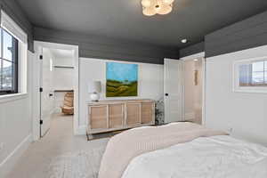 Bedroom featuring a textured ceiling, a spacious closet, multiple windows, and a closet