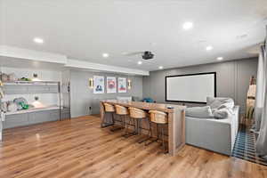 Cinema with bar area, a textured ceiling, and light hardwood / wood-style flooring