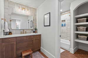 Bathroom with a textured ceiling, vanity, tile patterned flooring, and bathing tub / shower combination