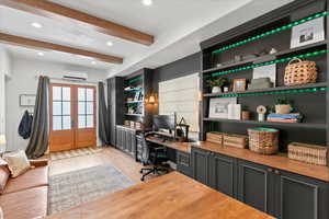 Home office with a wall mounted air conditioner, light hardwood / wood-style floors, french doors, and beam ceiling