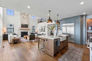 Kitchen with a center island with sink, a kitchen breakfast bar, stainless steel appliances, decorative light fixtures, and a fireplace