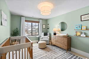 Bedroom with carpet floors, a textured ceiling, and a nursery area