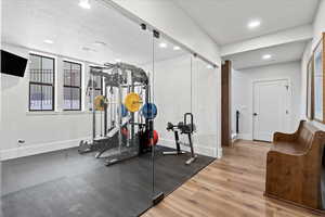 Exercise area with a textured ceiling and hardwood / wood-style floors