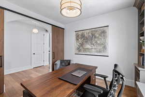 Home office with light hardwood / wood-style flooring and a notable chandelier