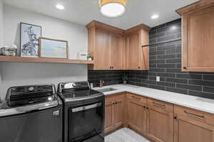 Washroom featuring sink, separate washer and dryer, and cabinets