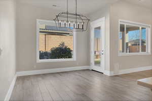 Unfurnished dining area featuring a chandelier and light hardwood / wood-style flooring