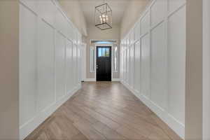 Foyer entrance with light hardwood / wood-style floors and a chandelier