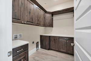 Laundry area featuring hookup for a washing machine, cabinets, light hardwood / wood-style flooring, and hookup for an electric dryer