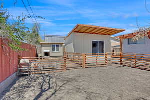 Back of house with an outbuilding, metal roof, and fence private yard