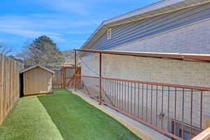View of yard featuring a storage shed, an outbuilding, a fenced backyard, and a gate