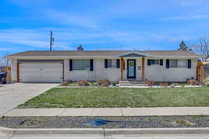 Ranch-style home with a garage, a front yard, brick siding, and concrete driveway