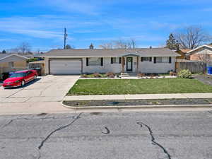 Ranch-style home featuring a front yard, an attached garage, fence, and brick siding