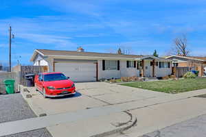 Single story home featuring fence, a front lawn, brick siding, an attached garage, and concrete driveway