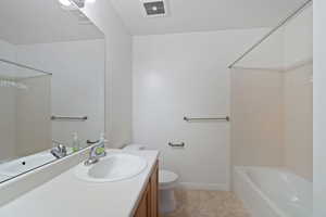 Full bathroom with vanity, tiled shower / bath, tile patterned floors, and toilet