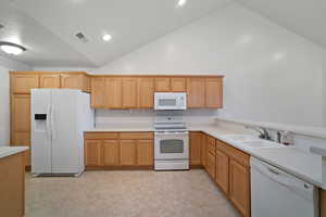 Kitchen featuring white appliances, high vaulted ceiling, and sink