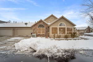 View of front of home with a garage and central air condition unit