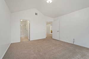 Unfurnished bedroom featuring lofted ceiling, light carpet, and ensuite bath