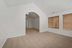 Carpeted spare room with vaulted ceiling