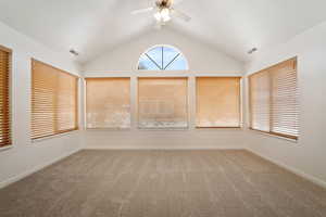 Spare room with vaulted ceiling, carpet flooring, and ceiling fan