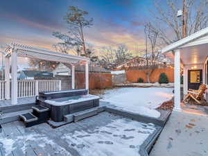 Snow covered patio featuring a deck, a pergola, and a hot tub