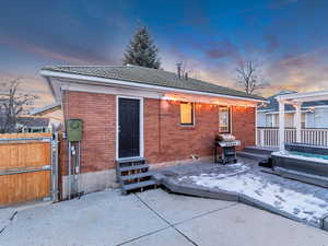 Back house at dusk featuring a patio and a covered hot tub