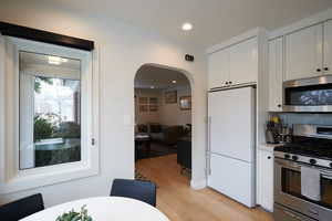 Kitchen featuring light hardwood / wood-style flooring, stainless steel appliances, and white cabinets