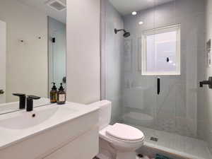 Bathroom featuring vanity, toilet, and a shower with shower door