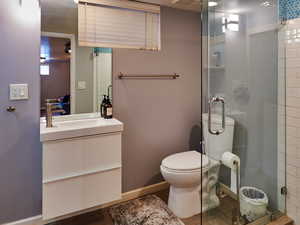 Bathroom with toilet, an enclosed shower, and vanity