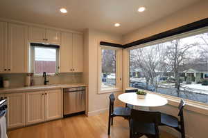 Kitchen featuring stainless steel dishwasher, sink, and light wood-type flooring