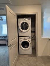 Laundry room with light carpet and stacked washer / dryer