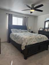 Carpeted bedroom with ceiling fan and a textured ceiling