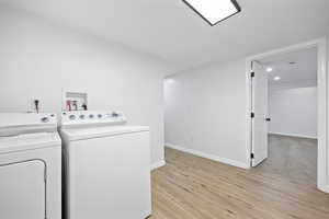 Clothes washing area featuring light hardwood / wood-style floors and washer and dryer