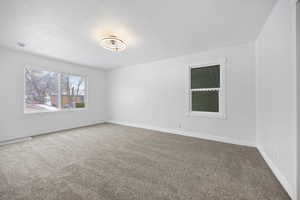 Carpeted empty room featuring a textured ceiling